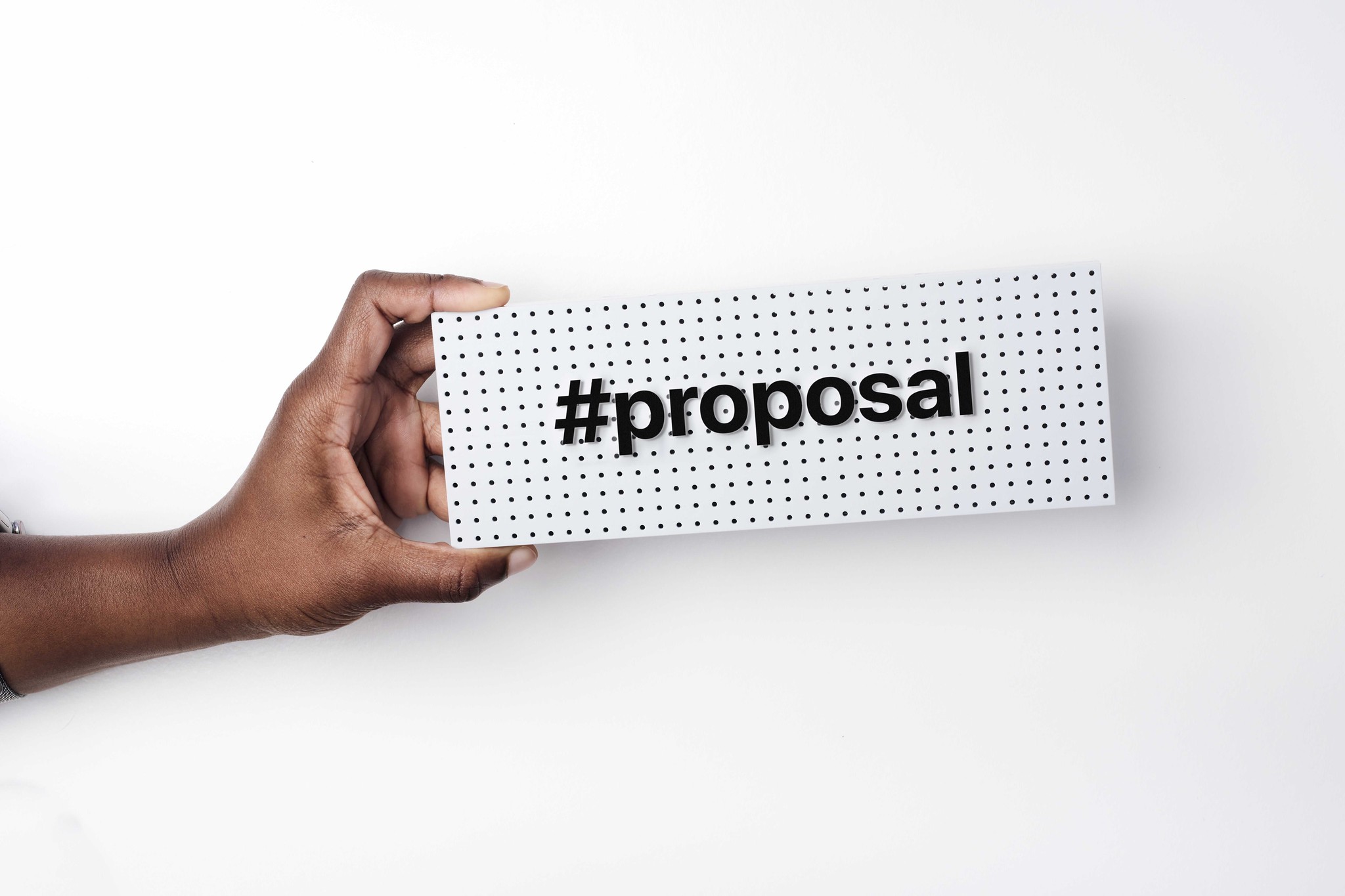 a hand hold a small sign with the words #proposa on it
